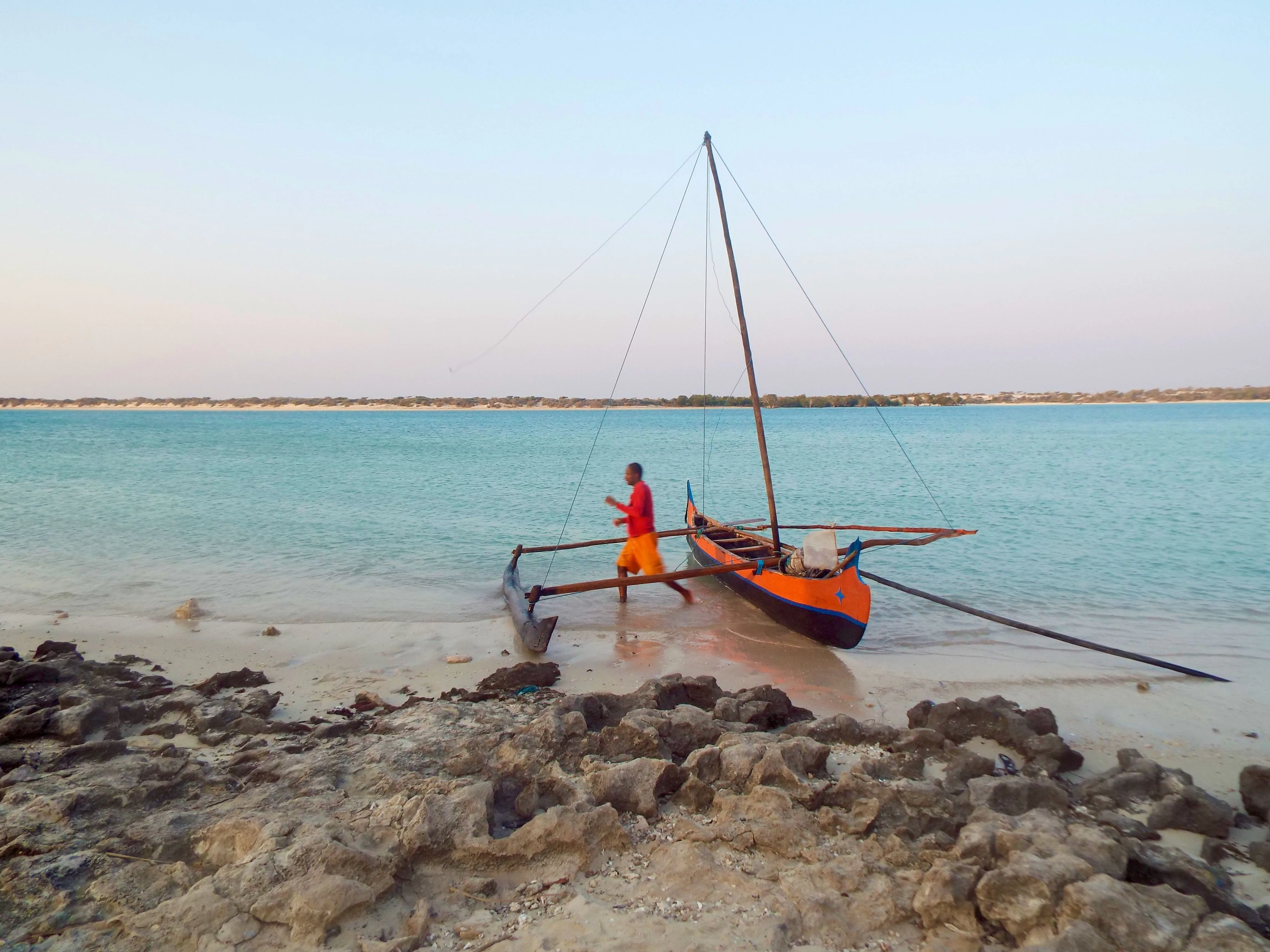 Image of a boat and man on a tropical beach.